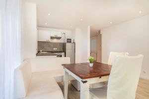 a kitchen and dining room with a wooden table and white chairs at Ferienwohnung Gartenstraße in Lindau-Bodolz