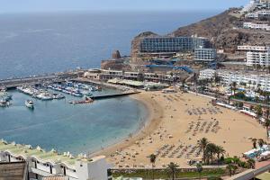 a beach with a bunch of people and boats in the water at Silent Flat in Puerto Rico de Gran Canaria