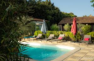 a pool with chairs and umbrellas next to a house at La Petite Maison De Noémie in Gras
