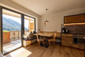 a kitchen with a table and chairs and a large window at Sonnleiten Sonnenalm in Collepietra