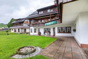 a building with a grassy yard in front of it at Cafe-Restaurant-Gästehaus Waldvogel in Feldberg