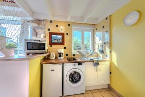 a kitchen with a washing machine and a microwave at La Maison du Gardien in Portsall +12 photos