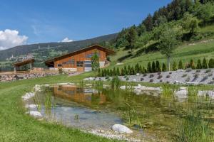 a house on a hill next to a pond at App Ringelblume Biohof Unterspisser in Laion