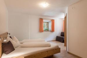 a white bedroom with a bed and a chair at App Ringelblume Biohof Unterspisser in Laion