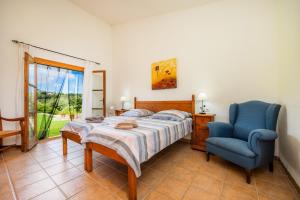 a bedroom with a bed and a blue chair at Finca Can Xerpeta in Son Servera +25 photos