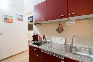 a kitchen with red cabinets and a sink at Kyma monolocale ad Otranto in Otranto