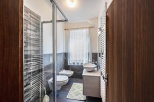 a bathroom with a toilet and a sink and a shower at Appartamento Primavera 2 in Moena