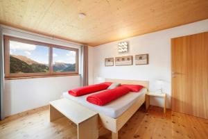 a bedroom with a bed with red pillows and a window at Joshof Talblick in Moso