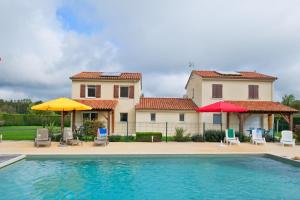 a house with a swimming pool and two umbrellas at Le Perchoir Avec Piscine et Clim in Savignac-les-Églises