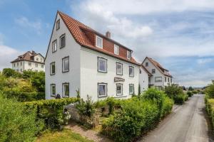 a white house with a red roof on a dirt road at Ferienwohnung Schloss-See-Bergblick in Waldeck
