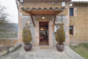 a house with two potted trees in front of a door at Cal Colom - Agroturisme in Puigreig