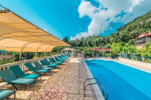 a row of lounge chairs next to a swimming pool at Andromaches large apartment 2 in Corfu