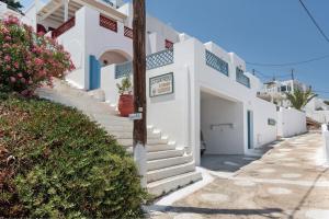 a house with white walls and stairs on a street at Lefkanthemo Apartment in Astypalaia