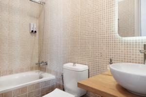 a bathroom with a sink and a toilet and a tub at Lefkanthemo Apartment in Astypalaia +22 photos