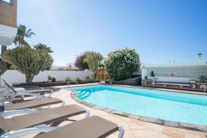 a swimming pool with lounge chairs next to a building at Villa Lea in Puerto del Carmen