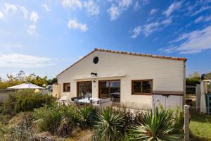 a white house with a patio in front of it at Maison Les Pieds Dans L'eau in Le Verdon-sur-Mer