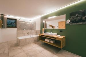a bathroom with a sink and a tub and a mirror at Archehof Hochzirm Lodge Anton in Campo Tures +17 photos
