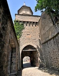 an archway in a stone building with a tower at Superbe appartement avec loggia in Super Besse +3 photos