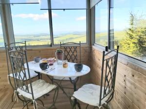 a table and chairs in a room with windows at Superbe appartement avec loggia in Super Besse
