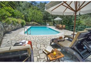 ein Schwimmbecken mit Stühlen, einem Sonnenschirm und einem Tisch in der Unterkunft Villa Dendro in Lákka