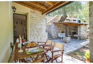eine Terrasse mit Tisch und Stühlen sowie einem Kamin in der Unterkunft Villa Dendro in Lákka