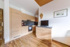 a kitchen with white walls and wooden cabinets at Sonnleiten der kleinen Bären 8 in Collepietra