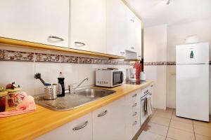 a kitchen with a sink and a white refrigerator at Ático Los Seres in Los Cristianos
