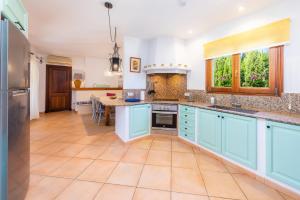 a large kitchen with blue cabinets and a table at Villa Rico in Portocolom