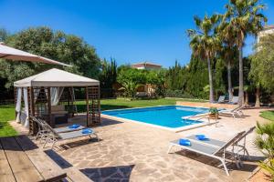 a swimming pool with chairs and a gazebo at Villa Rico in Portocolom