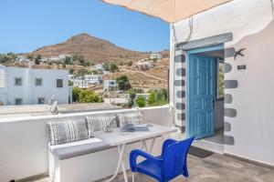 a balcony with a table and chairs and a blue door at Pico Bello Patmos 18 in Patmos +20 photos