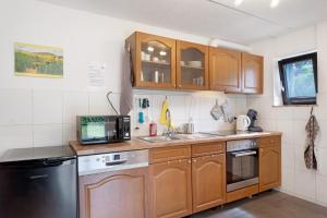 a kitchen with wooden cabinets and a sink and a microwave at Haus Marion in Todtnau +17 photos