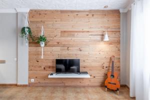 a room with a wooden wall with a computer and a guitar at Can Tosca in Jávea