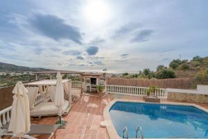 a swimming pool with umbrellas on a patio at Villa Padial in Torrox