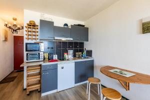 a kitchen with blue cabinets and a table in a room at Studio Cosy face à l'océan in Lacanau