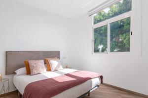 ein weißes Schlafzimmer mit einem Bett und einem Fenster in der Unterkunft Flamboyan 2 in Telde