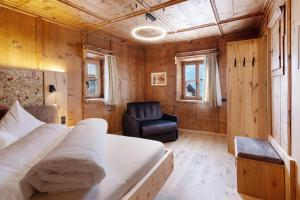 a bedroom with a bed and a chair at Bertollhof Weingenuss in Silandro