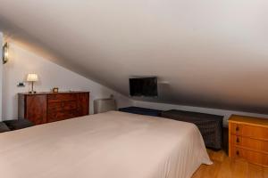 a bedroom with a white bed and a television at The Amphora Lodging in Furci Siculo