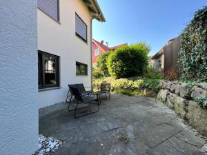 a patio with two chairs and a table next to a building at Lo Ferienwohnung in Friedrichshafen