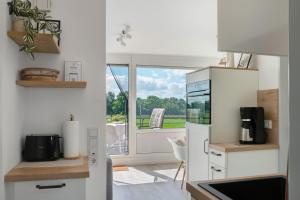 a kitchen with a white refrigerator and a balcony at Deichblick - in 5 min am Meer in Wangerland