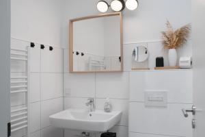 a white bathroom with a sink and a mirror at Deichblick - in 5 min am Meer in Wangerland +21 photos