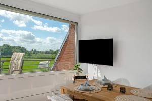 a living room with a large window with a flat screen tv at Deichblick - in 5 min am Meer in Wangerland