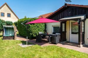 a patio with a table and a red umbrella at Ferienhaus Strandfloh in Wangerooge