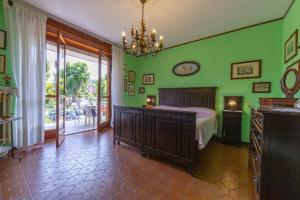 a bedroom with green walls and a bed and a chandelier at Jasmine in Cisterna dʼAsti