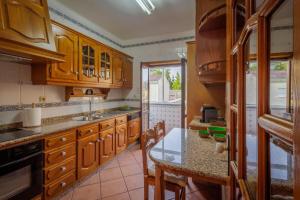 a kitchen with wooden cabinets and a glass table at Villa Vez in Arcos de Valdevez
