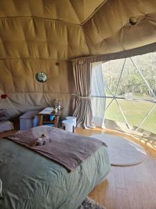 a bedroom with a bed in a tent with a large window at La Cabane aux Chevaux in Varages