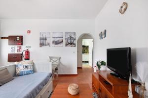 a living room with a bed and a tv at Casa Amarela in Tavira