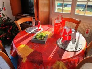 a table with a red table cloth with a plant on it at Gîte de Locmousteru in Moustéru +2 photos