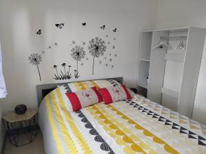 a bedroom with a bed with dandelions and butterflies on the wall at Gîte de Locmousteru in Moustéru
