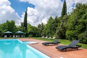 a swimming pool with two lounge chairs next to it at Rosaspina - Appartamento 3 in Capalbio