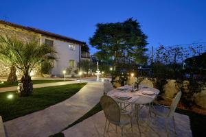 a dining table and chairs in a backyard at night at Abaye 2 Pinot - Charm Adults Only in Soiano del Lago